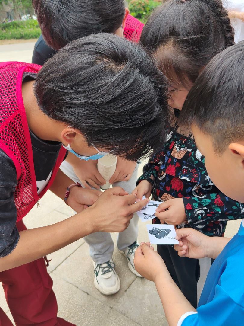 圖為志愿者陪小朋友一起判斷手中圖片對應的垃圾類型。